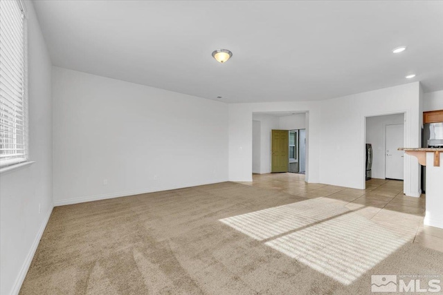 spare room featuring washer / clothes dryer and light carpet