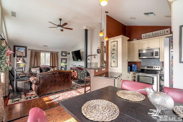 dining area featuring ceiling fan, vaulted ceiling, and hardwood / wood-style flooring