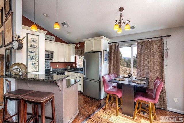 kitchen with decorative light fixtures, stainless steel appliances, an inviting chandelier, and sink