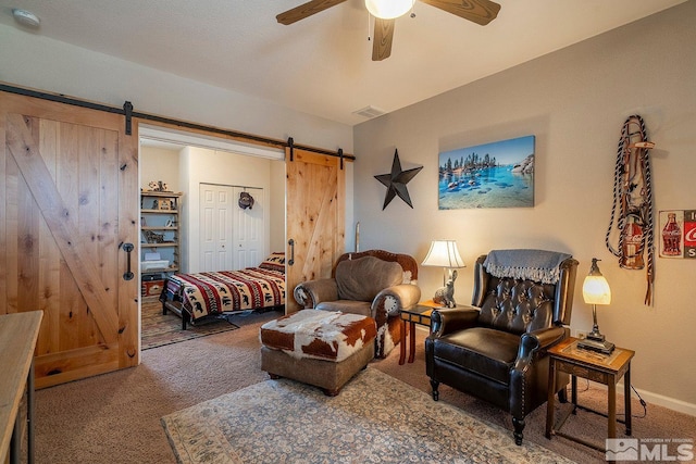 carpeted living room with a barn door and ceiling fan