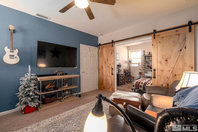 carpeted living room with a barn door and ceiling fan