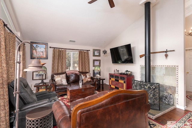 living room with hardwood / wood-style floors, ceiling fan, a wood stove, and lofted ceiling