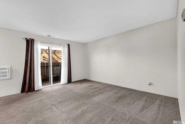 empty room featuring carpet flooring, a textured ceiling, and a wall mounted AC