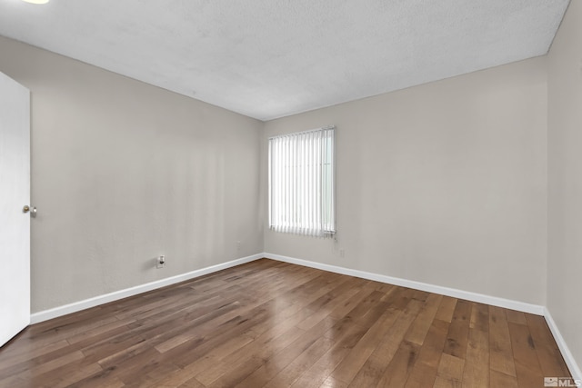 empty room with hardwood / wood-style floors and a textured ceiling