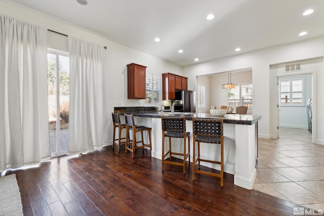 kitchen featuring stainless steel refrigerator, kitchen peninsula, a healthy amount of sunlight, and pendant lighting