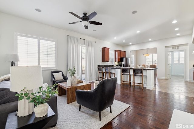 living room featuring ceiling fan, plenty of natural light, and dark wood-type flooring