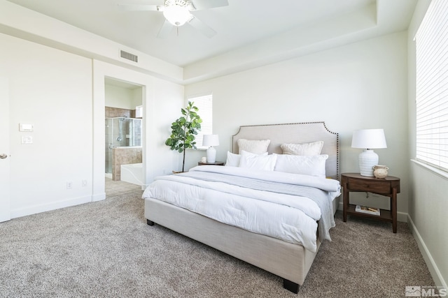 carpeted bedroom featuring ensuite bathroom, ceiling fan, and a tray ceiling