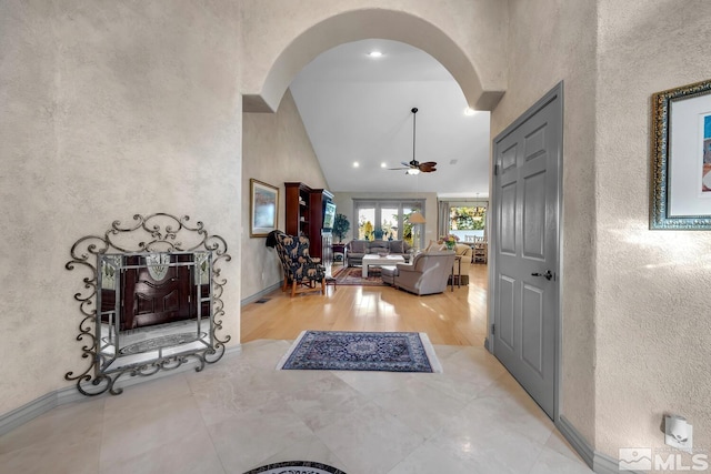 foyer entrance featuring light wood-type flooring, high vaulted ceiling, and ceiling fan