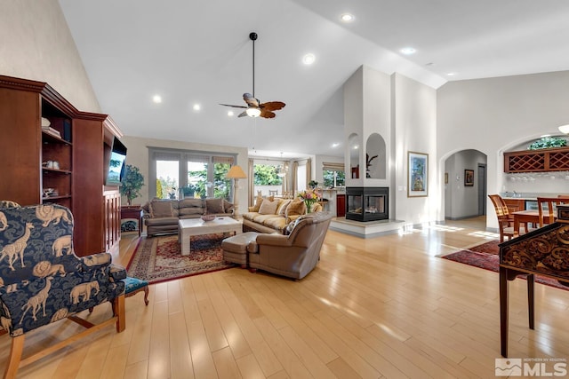 living room with ceiling fan, high vaulted ceiling, and light wood-type flooring