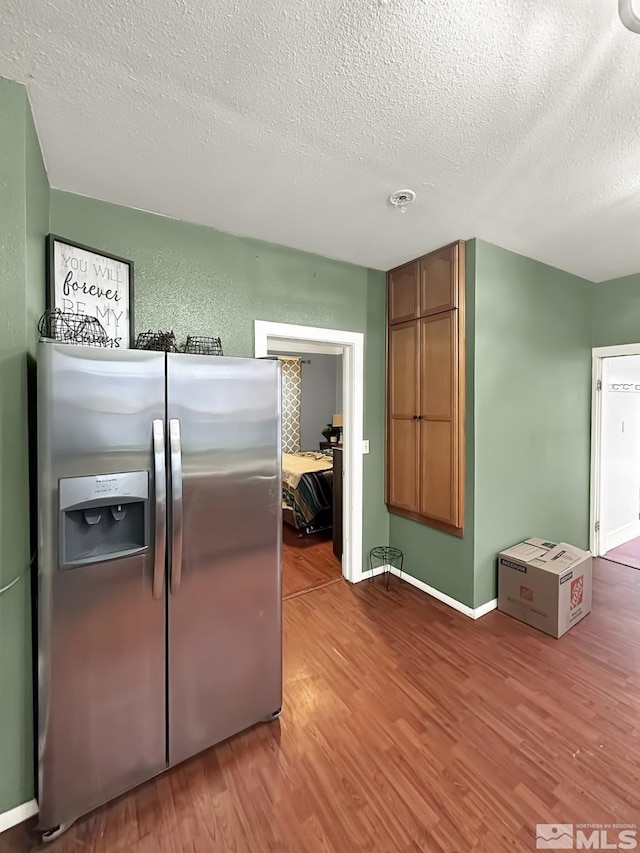 kitchen featuring stainless steel fridge with ice dispenser, a textured ceiling, and hardwood / wood-style flooring