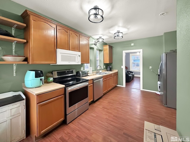 kitchen with light wood-type flooring, sink, and appliances with stainless steel finishes