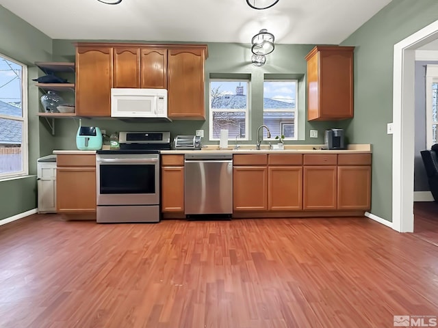 kitchen with stainless steel appliances, light hardwood / wood-style floors, and sink