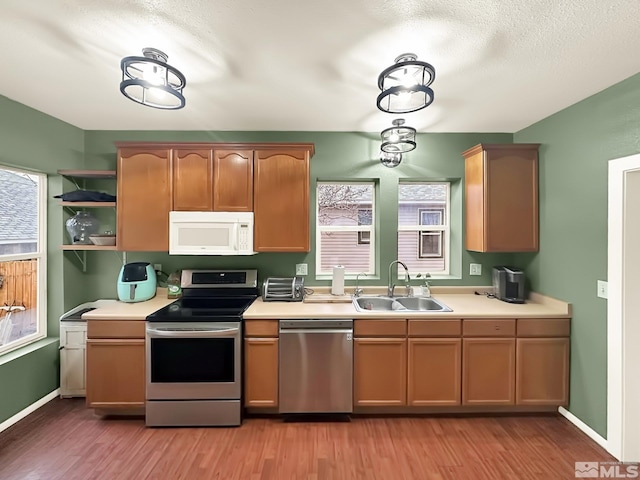 kitchen with appliances with stainless steel finishes, hardwood / wood-style flooring, and sink