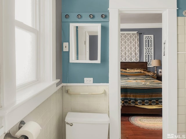 bathroom with toilet and tile walls