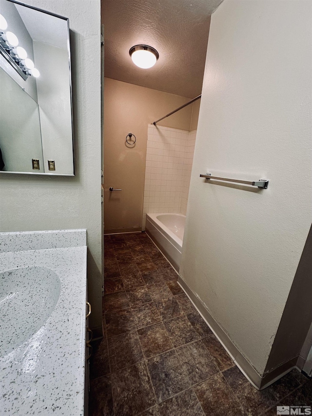 bathroom featuring sink, a textured ceiling, and tiled shower / bath