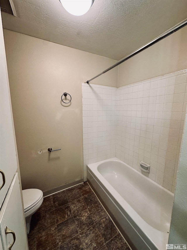 bathroom with shower / bathing tub combination, a textured ceiling, and toilet