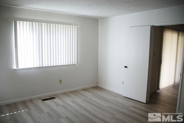 empty room with a textured ceiling and hardwood / wood-style floors