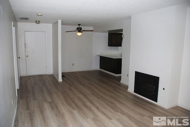 unfurnished living room with hardwood / wood-style floors, a textured ceiling, and ceiling fan