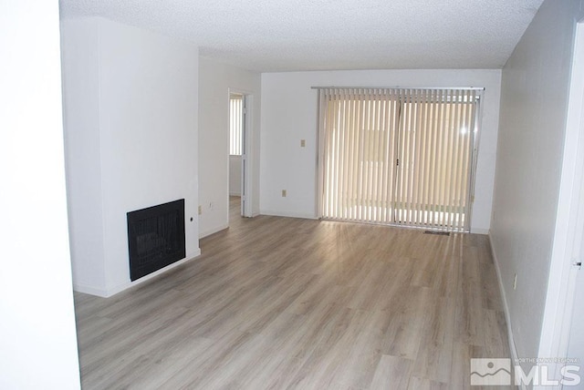 unfurnished living room featuring light hardwood / wood-style floors, a textured ceiling, and a wealth of natural light