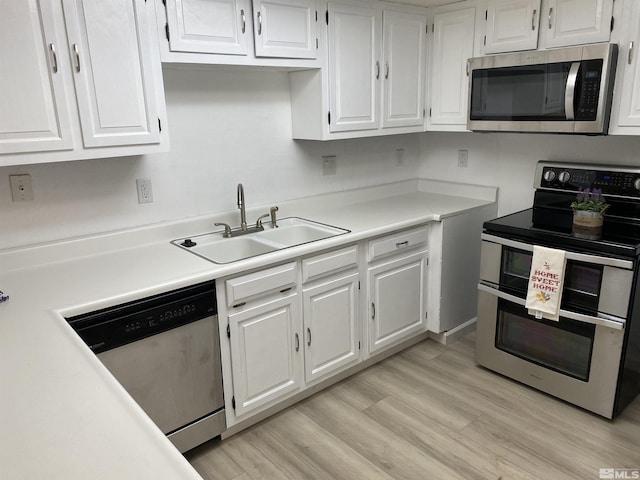 kitchen with appliances with stainless steel finishes, light hardwood / wood-style flooring, white cabinets, and sink