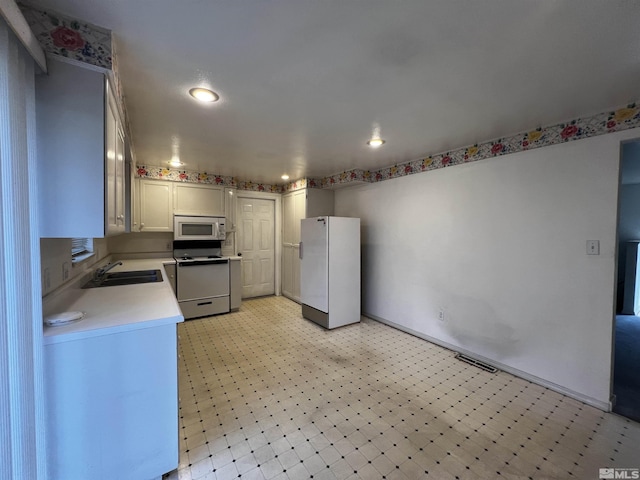 kitchen with white cabinetry, sink, and white appliances