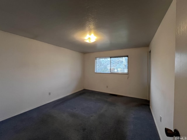 unfurnished room with dark colored carpet