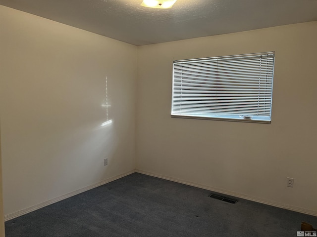 unfurnished room with dark colored carpet