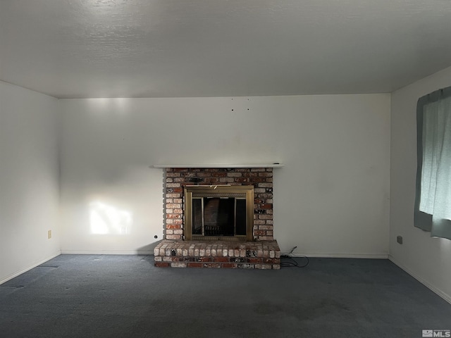 unfurnished living room featuring dark colored carpet, a textured ceiling, and a brick fireplace