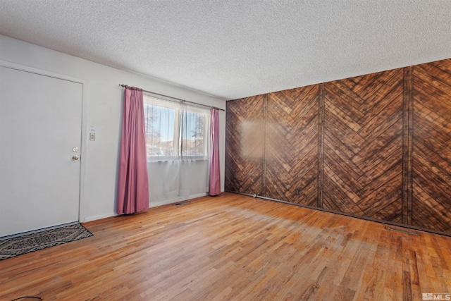 unfurnished room with light wood-type flooring and a textured ceiling