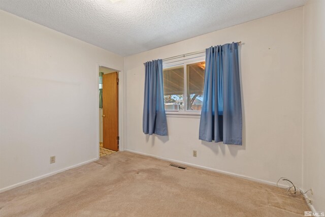 carpeted empty room with a textured ceiling