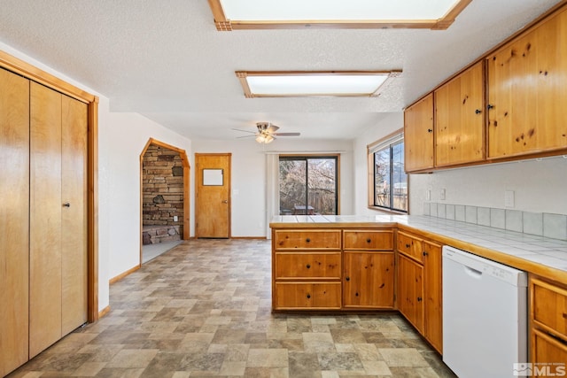 kitchen featuring ceiling fan, dishwasher, kitchen peninsula, tile countertops, and a textured ceiling