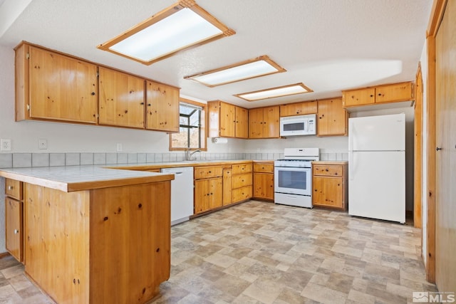 kitchen featuring a textured ceiling, sink, white appliances, and kitchen peninsula