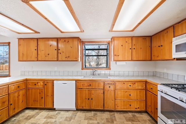 kitchen featuring tile counters, sink, a healthy amount of sunlight, and white appliances