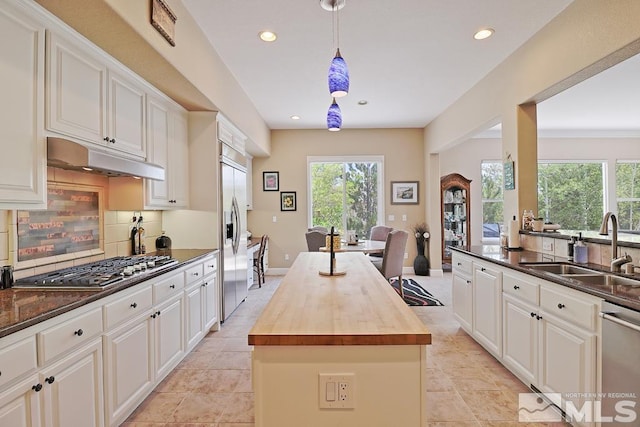 kitchen with wood counters, a center island, white cabinetry, and sink