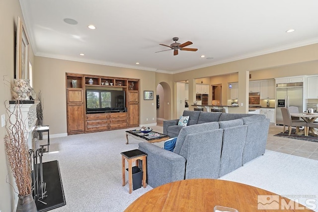 carpeted living room with a fireplace, ceiling fan, and crown molding