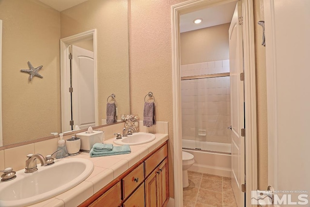 full bathroom featuring tile patterned floors, vanity, bath / shower combo with glass door, and toilet