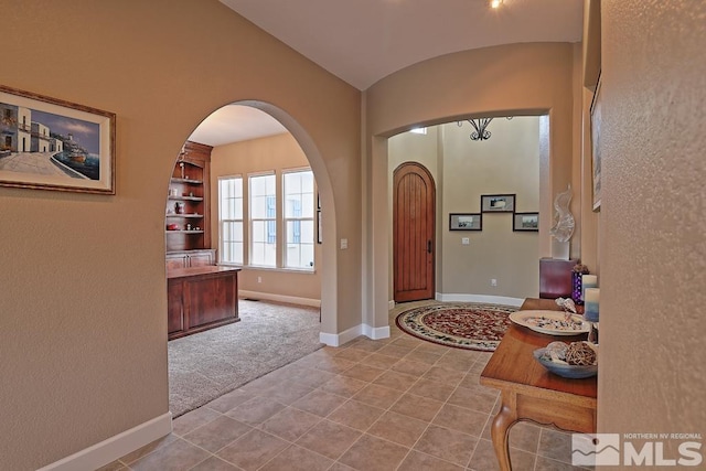 entryway with light carpet and lofted ceiling