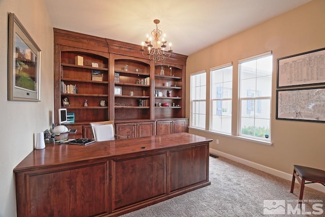 carpeted home office featuring an inviting chandelier