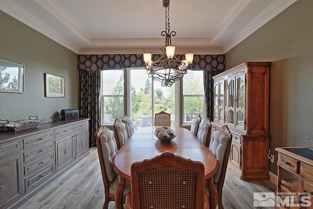 dining room with light hardwood / wood-style floors, a tray ceiling, and a notable chandelier