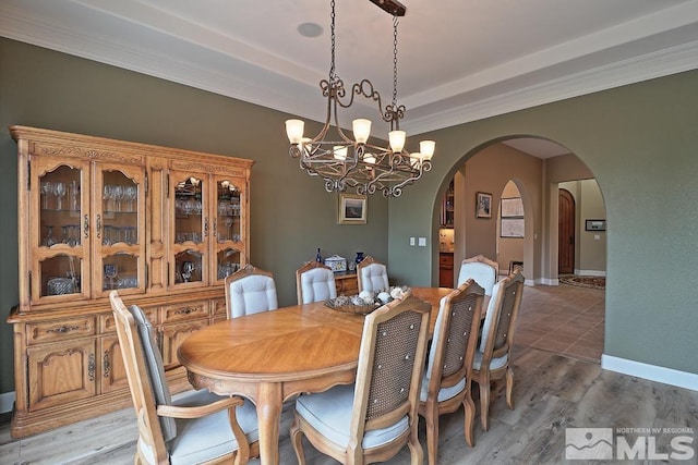 dining area featuring wood-type flooring, ornamental molding, and a chandelier