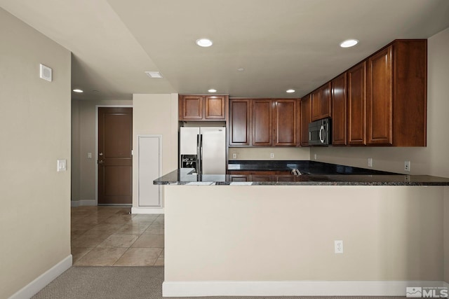 kitchen with dark stone countertops, kitchen peninsula, stainless steel appliances, and light tile patterned floors