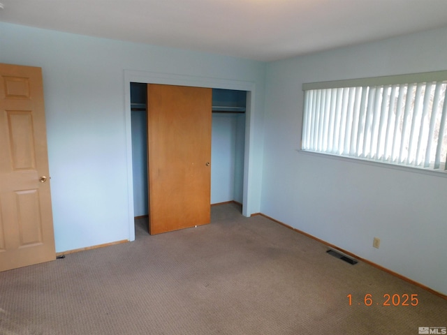 unfurnished bedroom with light colored carpet and a closet