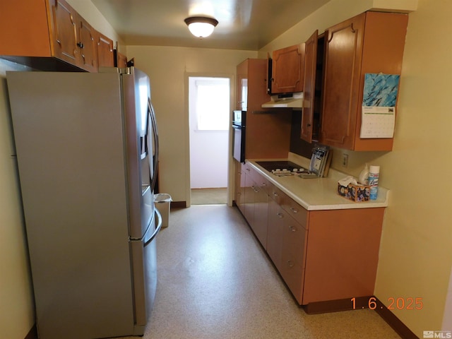 kitchen featuring oven, stainless steel fridge, and gas stovetop