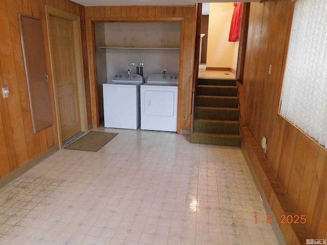 washroom with washing machine and clothes dryer and wood walls