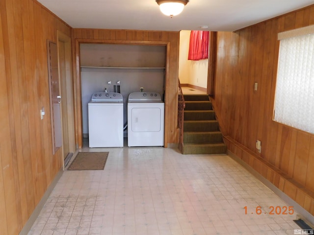 clothes washing area featuring washing machine and clothes dryer and wooden walls