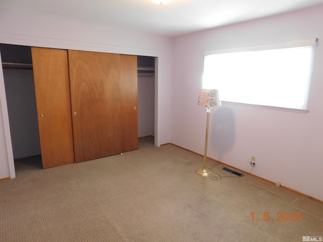 unfurnished bedroom featuring light carpet and a closet