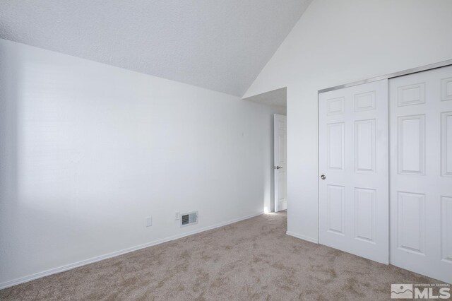 unfurnished bedroom featuring light carpet, a closet, and vaulted ceiling