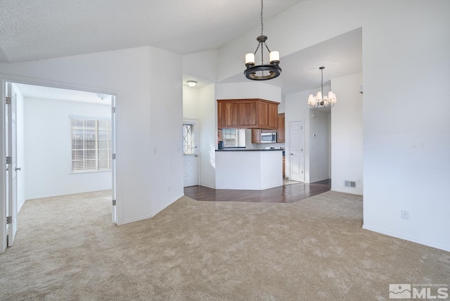 kitchen with carpet flooring, pendant lighting, lofted ceiling, and a notable chandelier