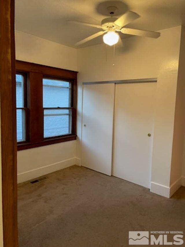 unfurnished bedroom with ceiling fan, a closet, and carpet floors