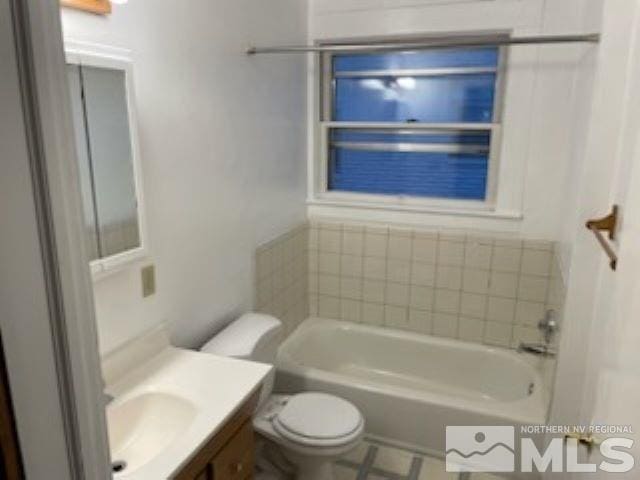 bathroom featuring vanity, toilet, and a tub to relax in